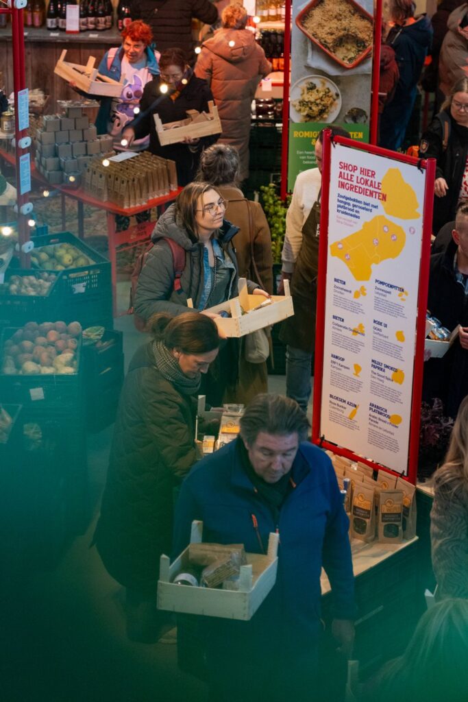 Bezoekers met houten kistjes vol lokale producten op de Polder Parade markt